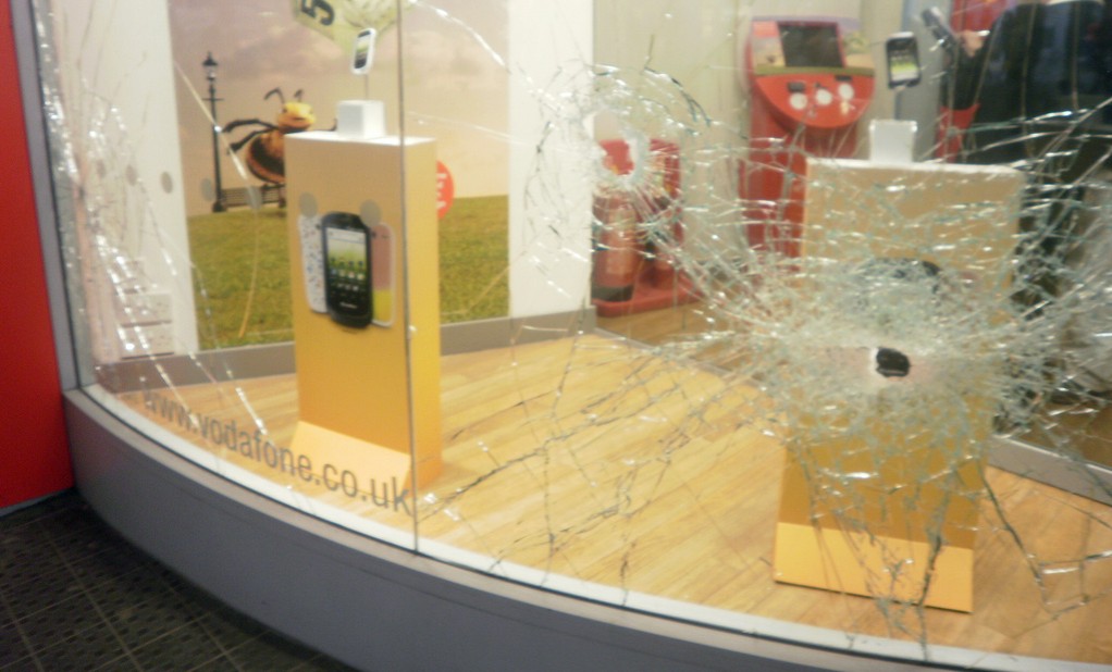 Vandalism - storefront glass with multiple bullet holes and shattered glass