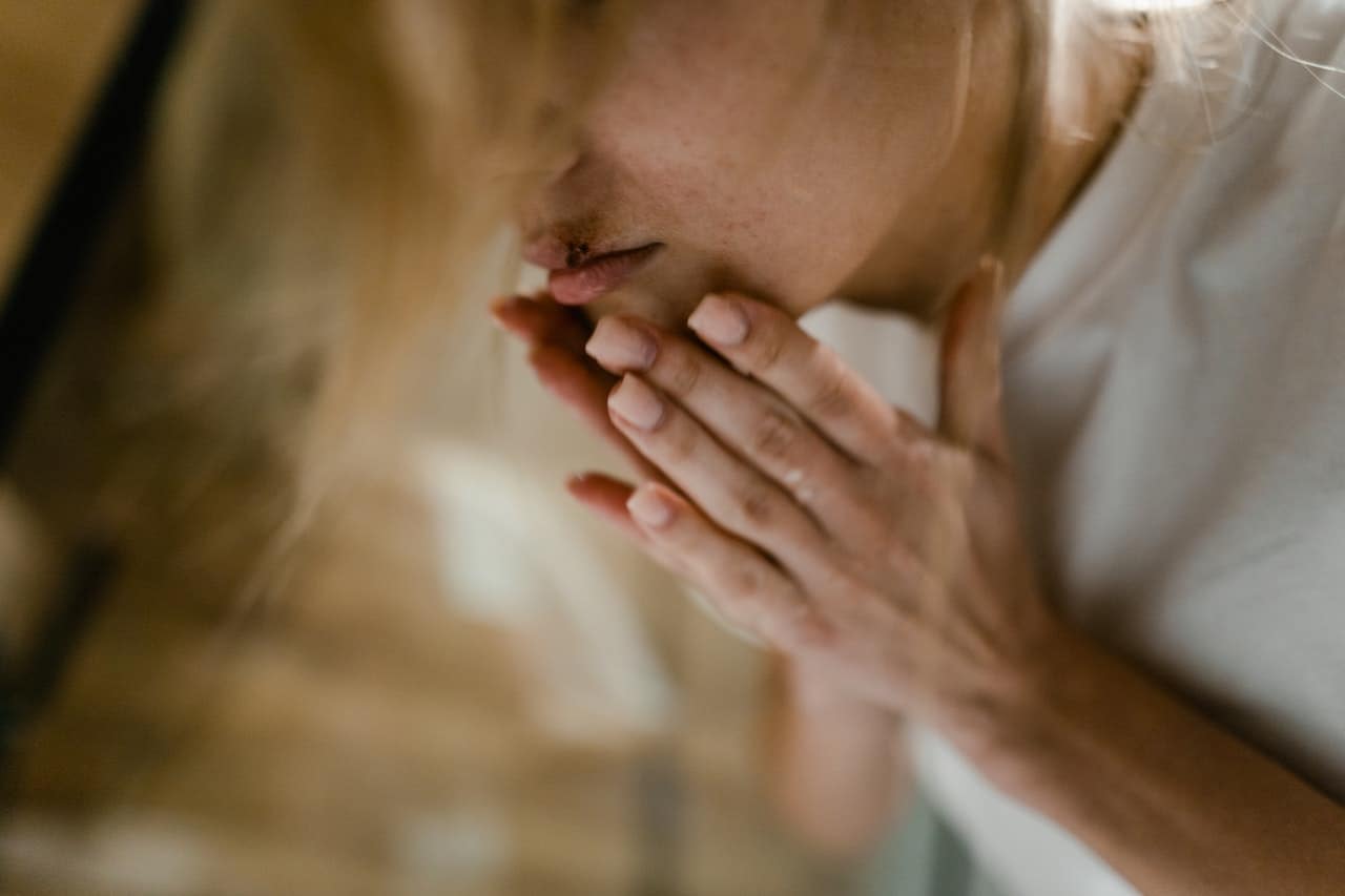 woman holding hands to bloody lip