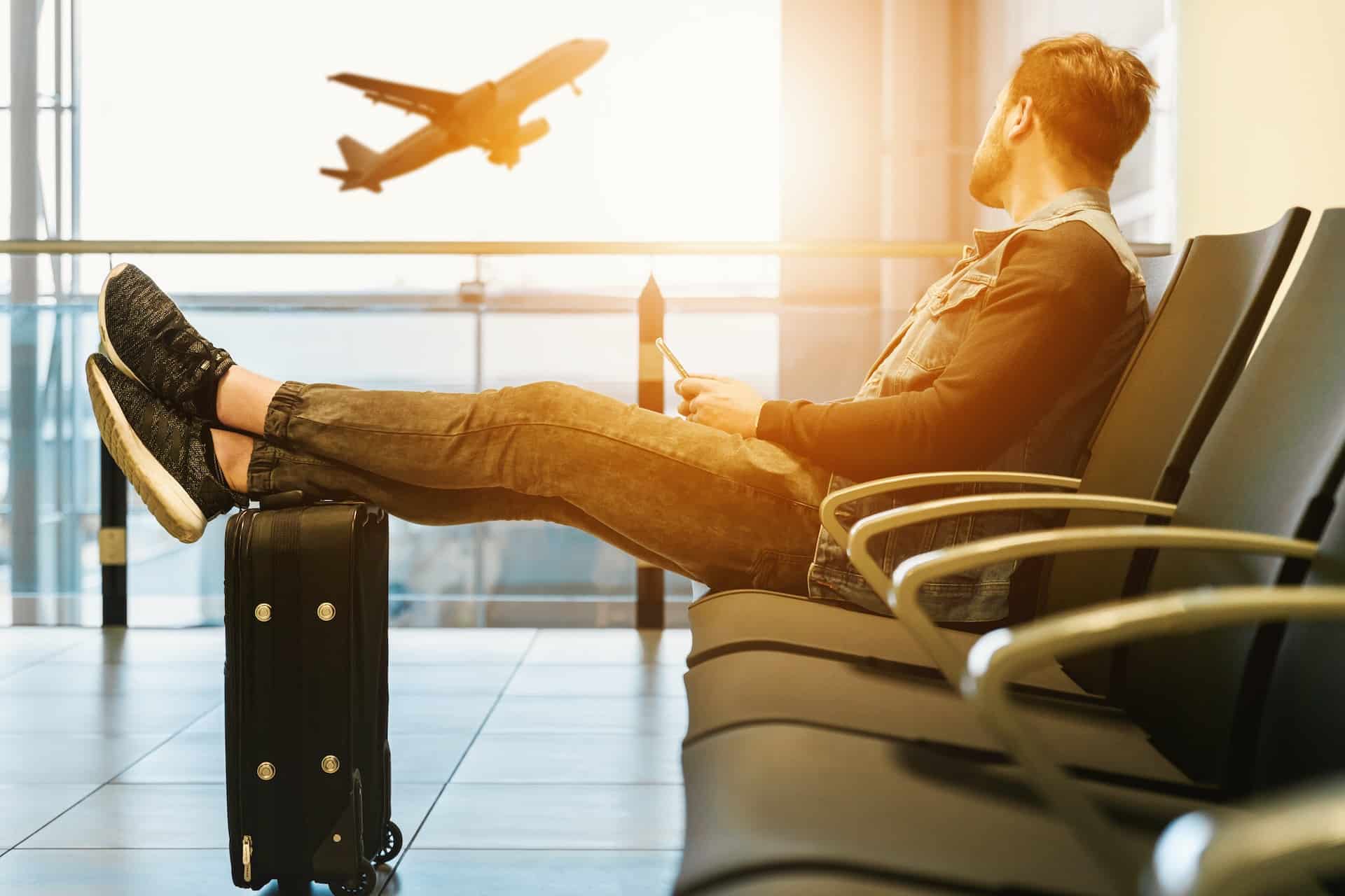 man waiting for a flight with a plane in the background - travel while on probation