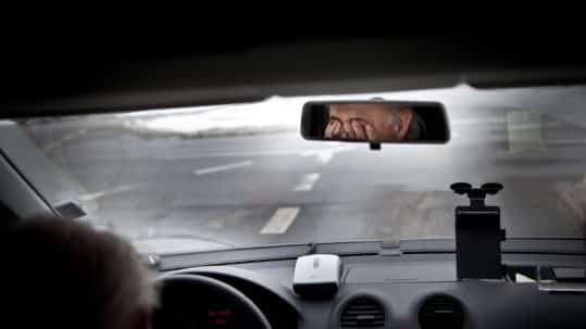 man rubbing his eyes behind the wheel of a car- drowsy driving