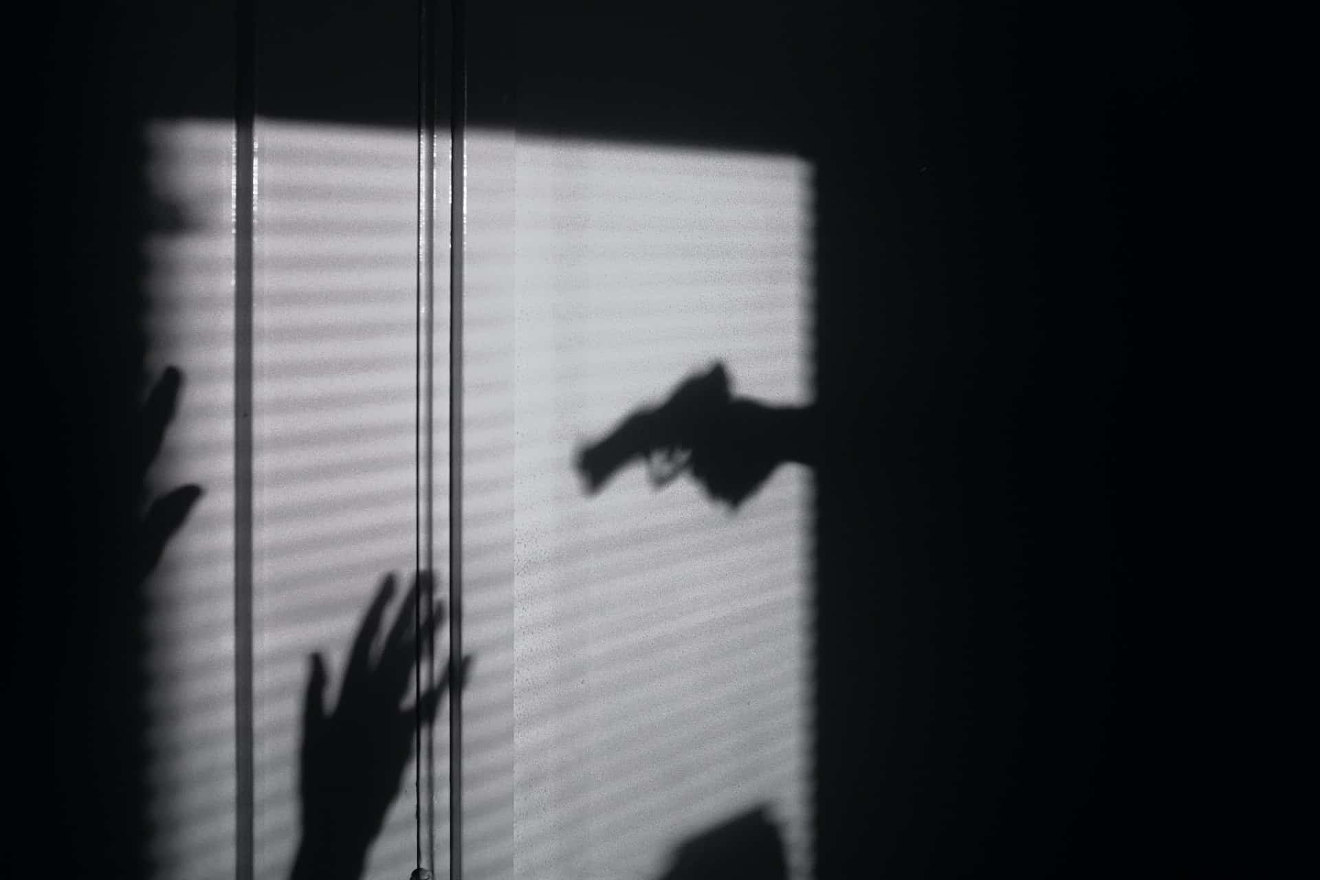 silhouette of person with gun and others with hands up - murder and manslaughter difference