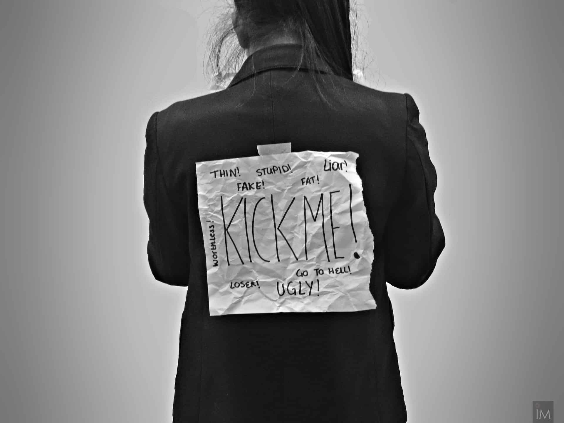 woman with a sign on her back -criminal hazing