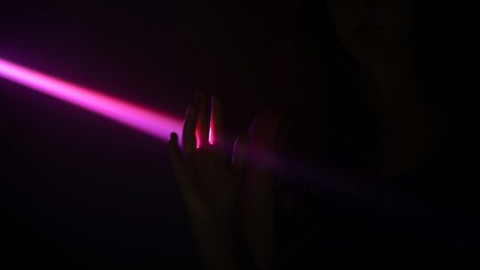 pink laser light with hand in shadow