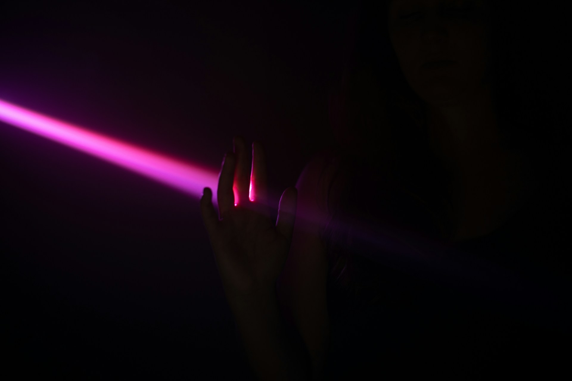 pink laser light with hand in shadow