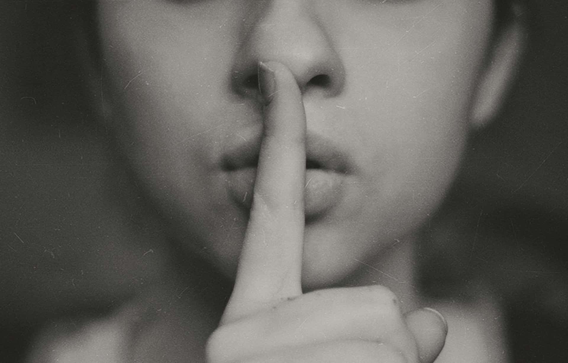 person making the quiet sign with their pointer over their lips