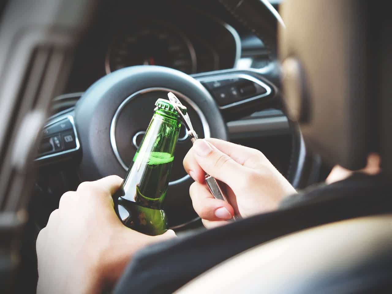 driver opening beer bottle in car