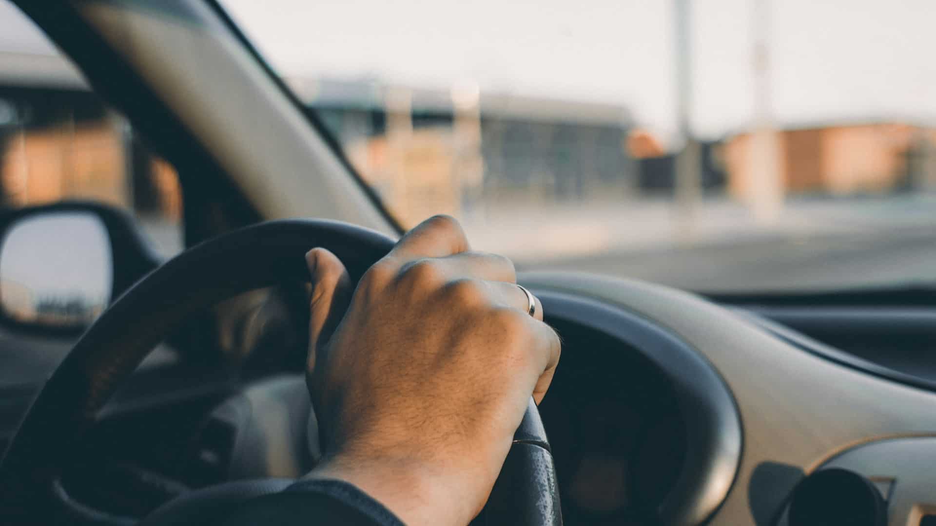 hand on steering wheel of a car